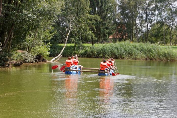 Kinder paddeln in Booten über den Fluss im Feriencamp in den Niederlanden