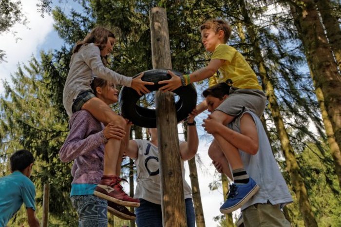 Kinder heben einen Reifen über einen Stamm im Feriencamp in den Niederlanden