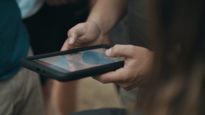 Zwei Hände halten ein Tablet im Kinderferienlager in Sachsen