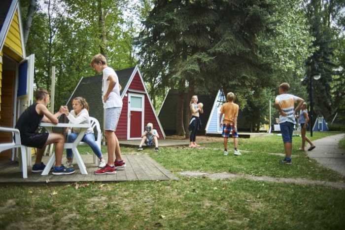 Kinder spielen und unterhalten sich vor kleinen Hütten im Kinderferienlager in Sachsen
