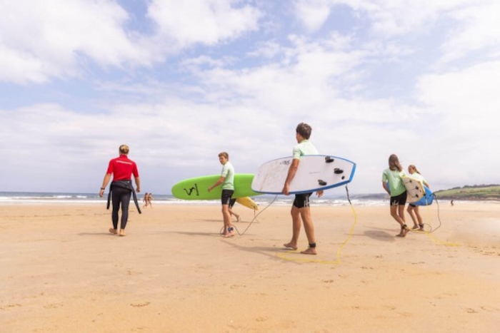 Jeugd wandelt over strand met surfplanken op reis.
