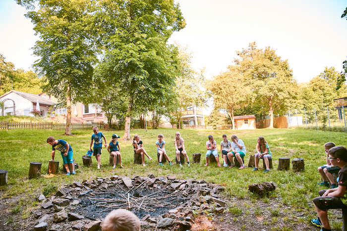 Kindergruppe sitzt auf Baumstümpfen im Englischcamp am Edersee
