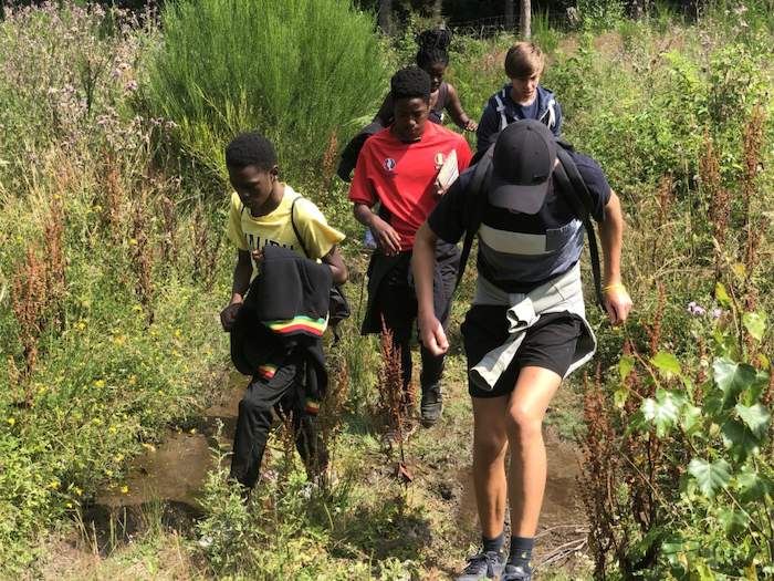 Jongeren marcheren door de plassen op avonturenkamp.