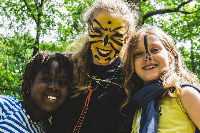 Op zomerkamp Hasselt lachen meisjes met geschminkte gezichten naar de camera.