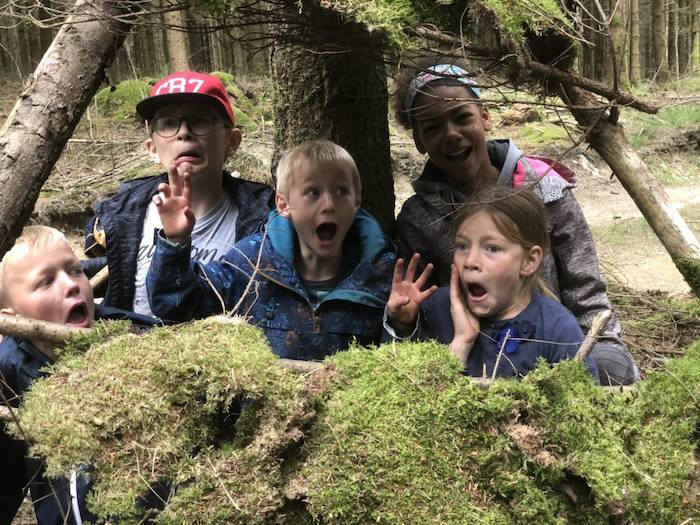 Kinderen in bos trekken gekke bekken op avonturenkamp.