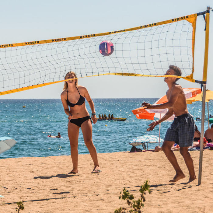 Jongeren spelen volleybal op het zonnige Spaanse strand.