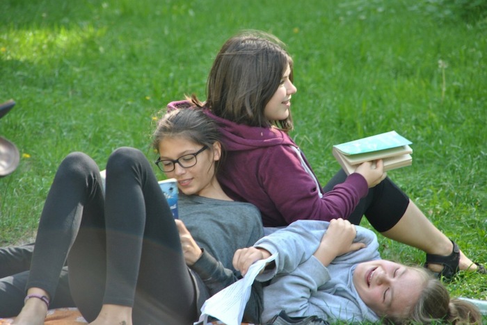 Mädchen liegen auf der Wiese im Kreativcamp und lesen