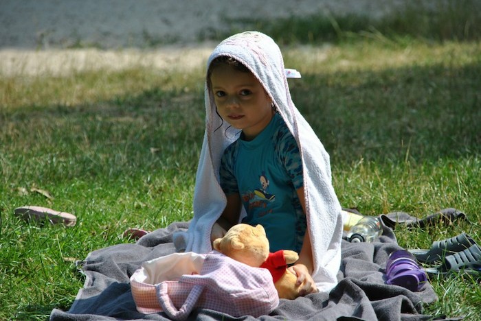 Mädchen im Handtuch sitzt auf einer Wiese im Künstlercamp
