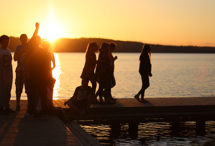 Die Jugendlichen der Jugendreise Callela laufen auf einem Steg im Sonnenuntergang