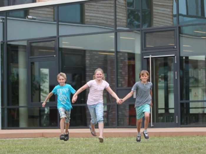 Kinder hüpfen begeistert vor der Jugendherberge des Wassersportcamps Ratzeburg