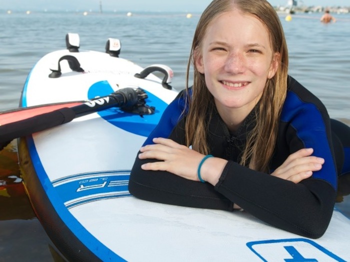 Mädchen entspannt sich auf dem Surfbrett im Wassersportcamp Ratzeburg