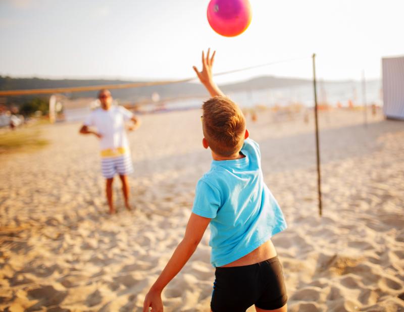 Junge spielt Volleyball am Strand