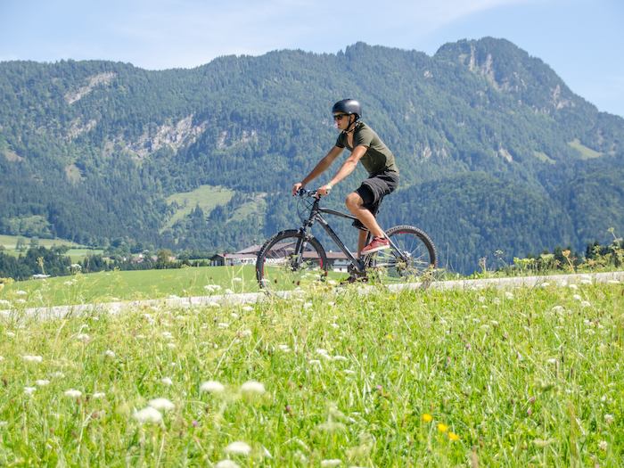 Jugendlicher fährt Fahrrad vor Berglandschaft im Actioncamp Österreich