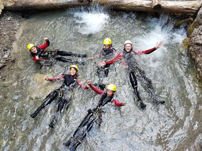 Kinder baden in Ausrüstung im flachen See im Actioncamp Österreich
