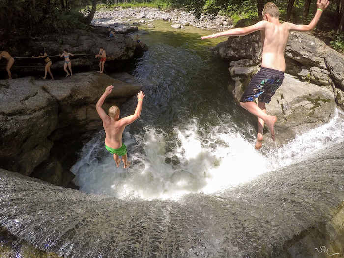 Zwei Jungen springen in einen Wasserfall im Actioncamp Österreich