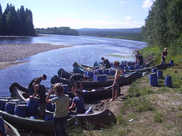 Jugendliche mit Kayaks am Fluss
