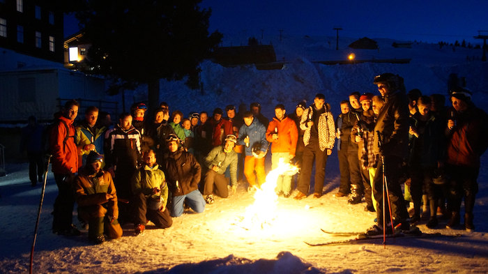 Un groupe de jeunes autour d’un feu de camp en colonie de vacances ski ado 