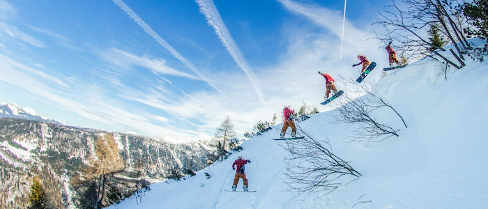 Junge macht im Osterferienlager tricks mit dem Snowboard
