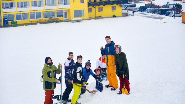 Gruppe schaufelt Schnee auf der Skifreizeit Österreich