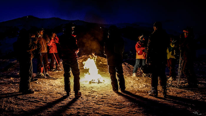 Gruppe ist nachts um ein Lagerfeuer versammelt auf der Skifreizeit Österreich