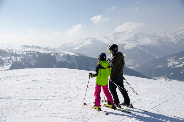 Zwei Skifahrer einer Ferien-Reise stehen auf dem Berg
