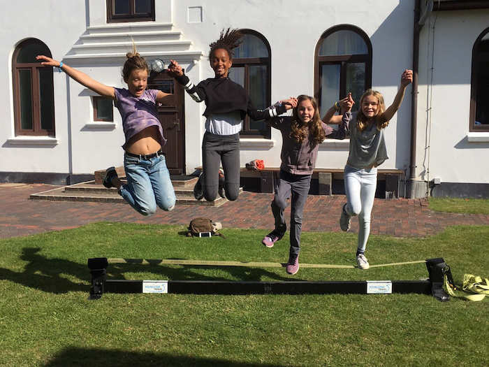 Vier Mädchen springen auf der Slackline im Ferienlager auf Sylt