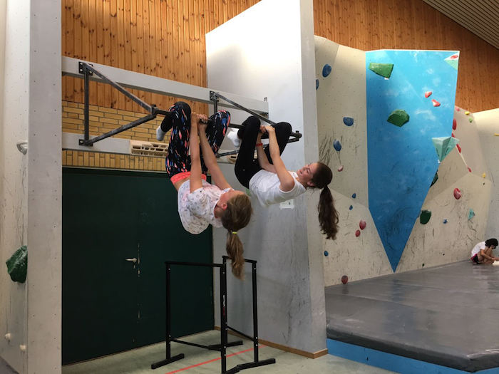 Zwei Mädchen lassen sich in der Sporthalle von einer Stange hängen im Ferienlager auf Sylt