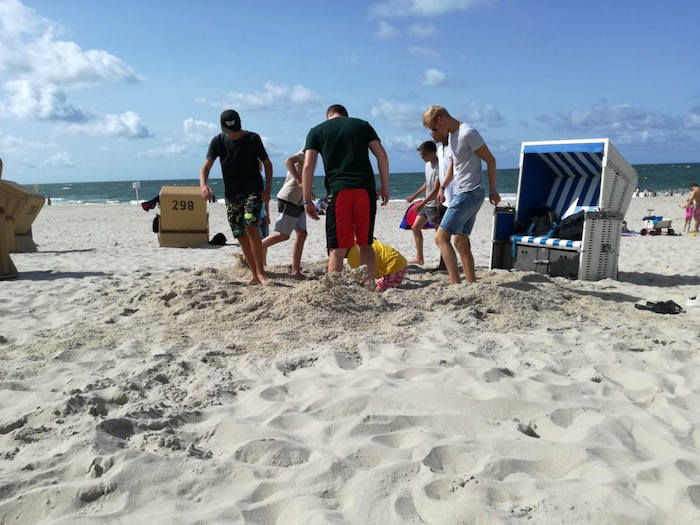 Jungen buddeln gemeinsam am Strand im Ferienlager auf Sylt