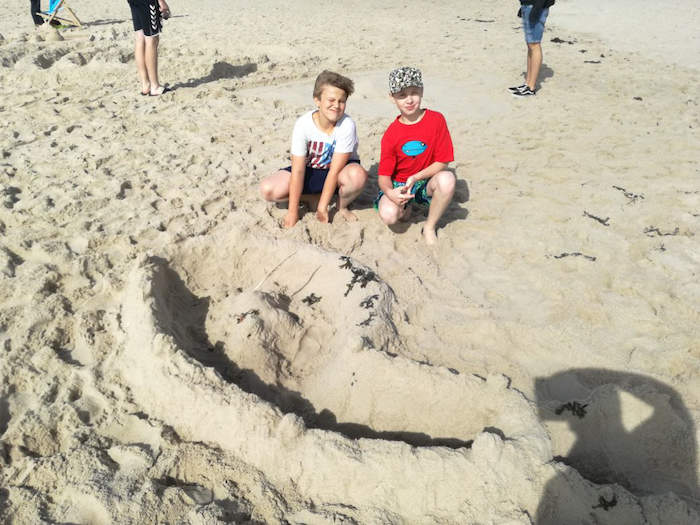 Jungen präsentieren ihre Sandburg im Ferienlager auf Sylt