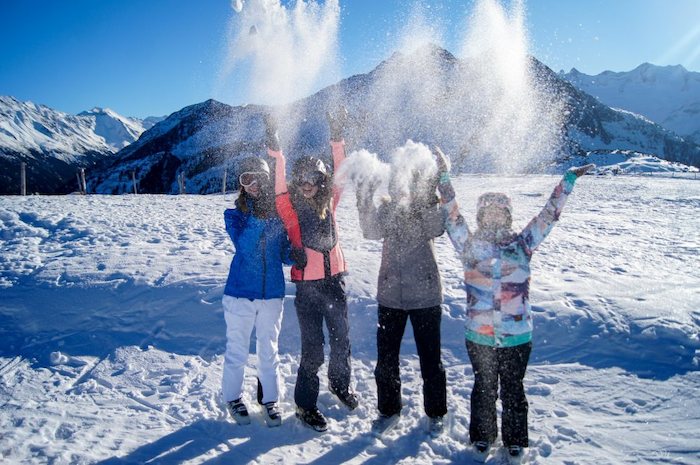 Jugendliche werfen Schnee in die Luft auf der Skifreizeit Österreich