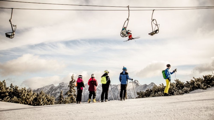 Skifahrer stehen unter dem Skilift auf der Skifreizeit Österreich