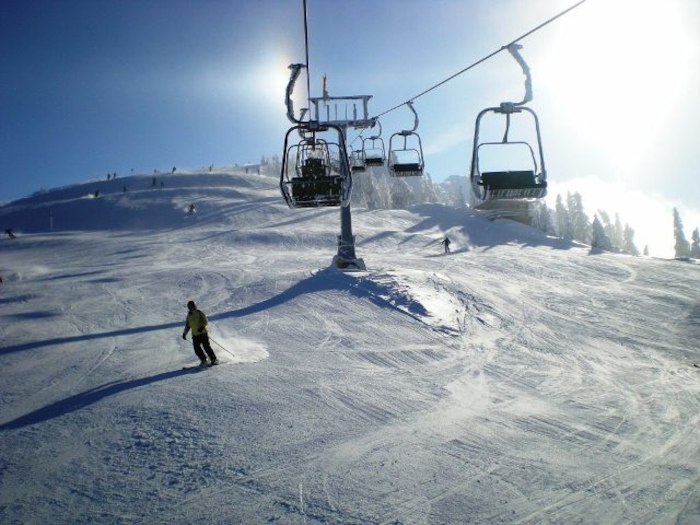 Bei Sonnenschein fährt ein Teilnehmer des Skicamps gerade unter den schwebenden Gondeln die Piste hinunter