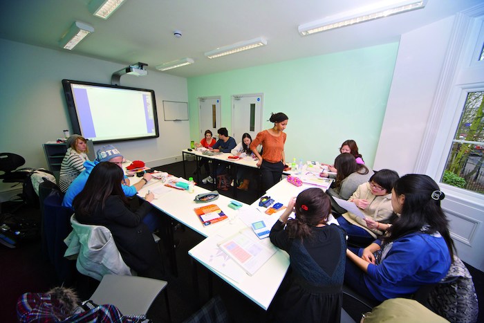 Les jeunes en voyage linguistique à Londres sont assis dans une petite salle de classe