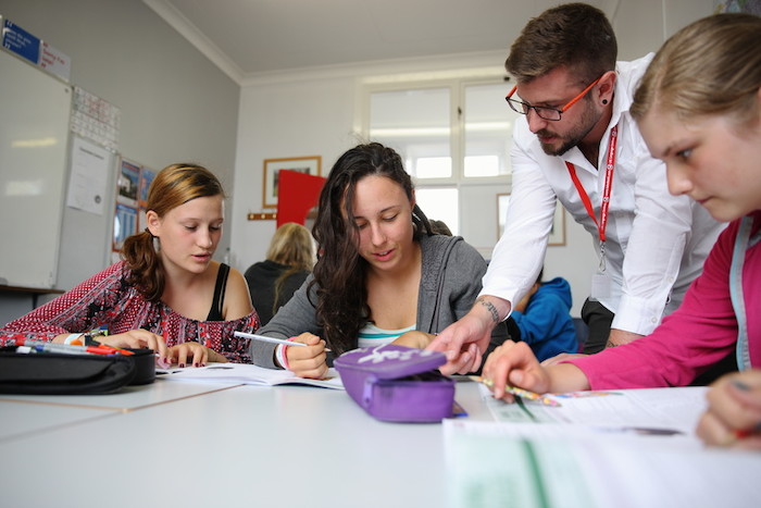 Ein Lehrer hilft den Jugendlichen beim Lernen auf Jugendsprachreise