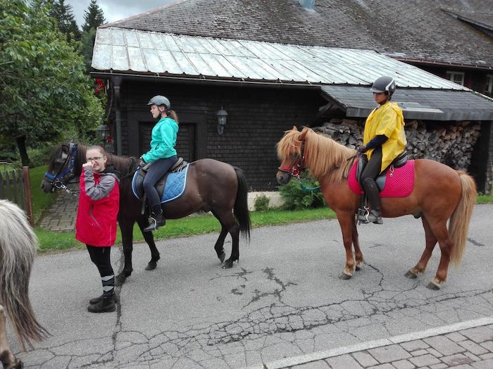 Zwei Mädchen reiten auf schwarzem und braunem Pferd im Lerncamp in Baden-Württemberg