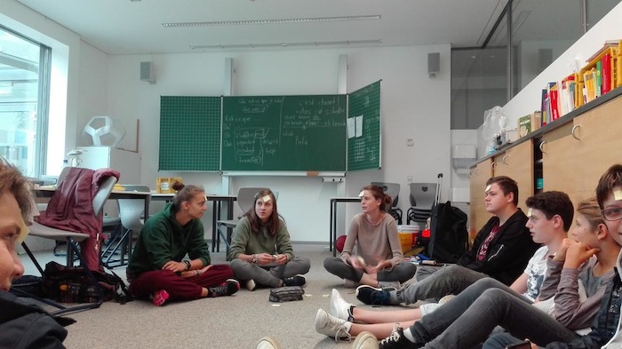 Kinder unterhalten sich auf dem Boden des Klassenzimmers im Lerncamp in Baden-Württemberg