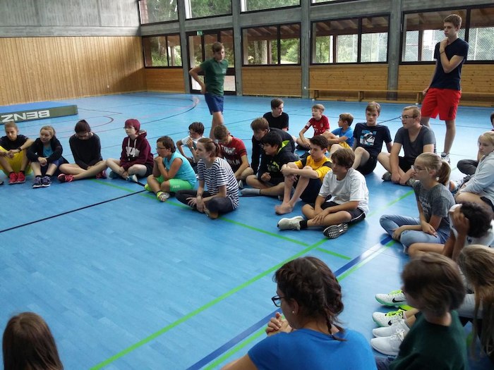 Jugendliche sitzen auf dem Boden der Turnhalle im Lerncamp in Baden-Württemberg