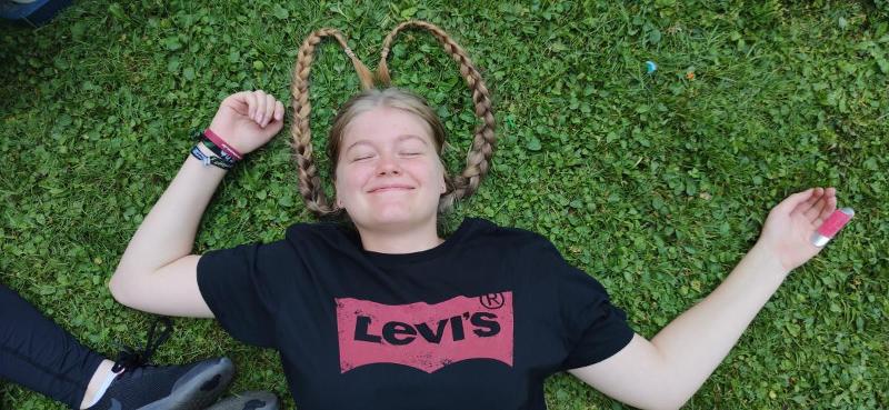 Ein Mädchen eines Englisch-Sprachcamps Bayern liegt mit einer lustigen Frisur auf dem Boden