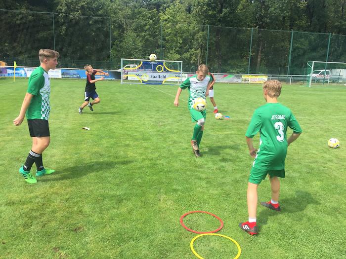 Ein Gruppe Jungs jongliert den Ball durch einen Parkour im Fussballcamp.