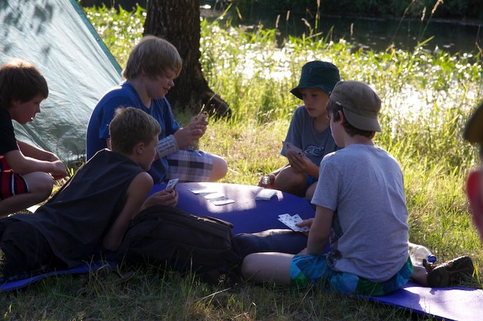Jungs spielen draußen im Schatten Karten im Ferienlager im Spreewald