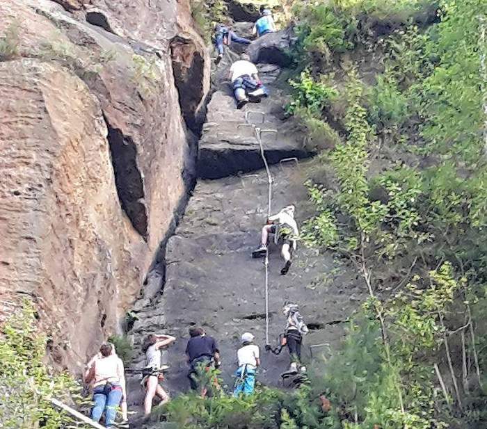 Auf Kanureise klettern Jugendliche einen Felsen hoch