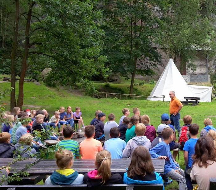 Gruppe sitzt auf Bänken im Jugendlager