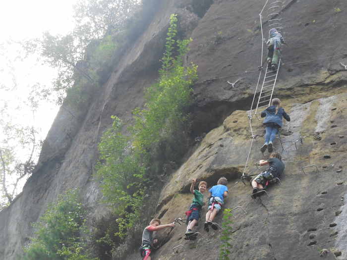 Kinder klettern an einem Naturfelsen auf Kanureise