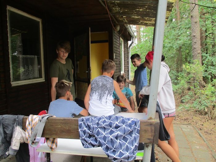 Gruppe Jungs sitzt vo ihrem Bungalow im Ferienlager in Brandenburg