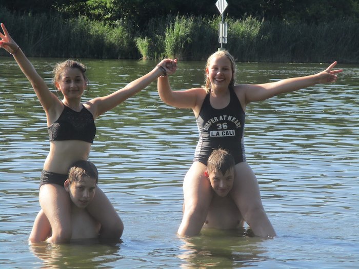 Mädchen sitzen auf den Schultern von zwei Jungs im Wasser im Ferienlager in Brandenburg