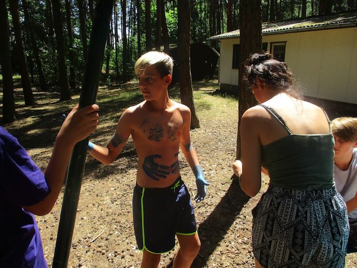 Junge nimmt angemalt einen Stamm in die Hand im Action-Feriencamp bei Berlin