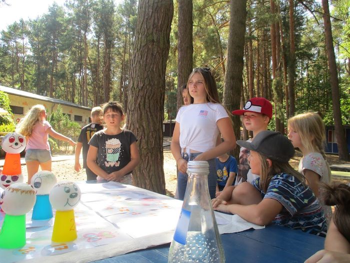 Kinder sitzen vor ihren gebastelten Dingen im Action-Feriencamp bei Berlin
