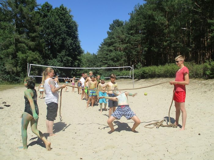 Kinder spielen Limbo am Strand im Action-Feriencamp bei Berlin