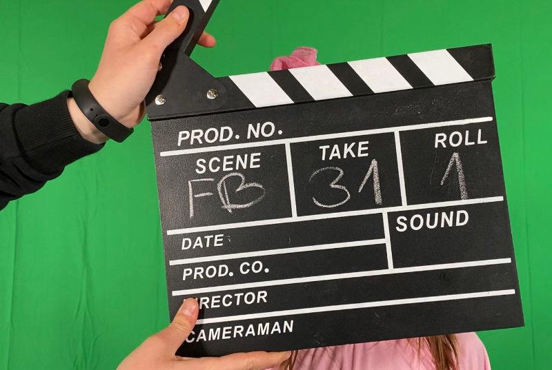 Eine Filmklappe wird im Film-Camp vor einen Greenscreen gehalten