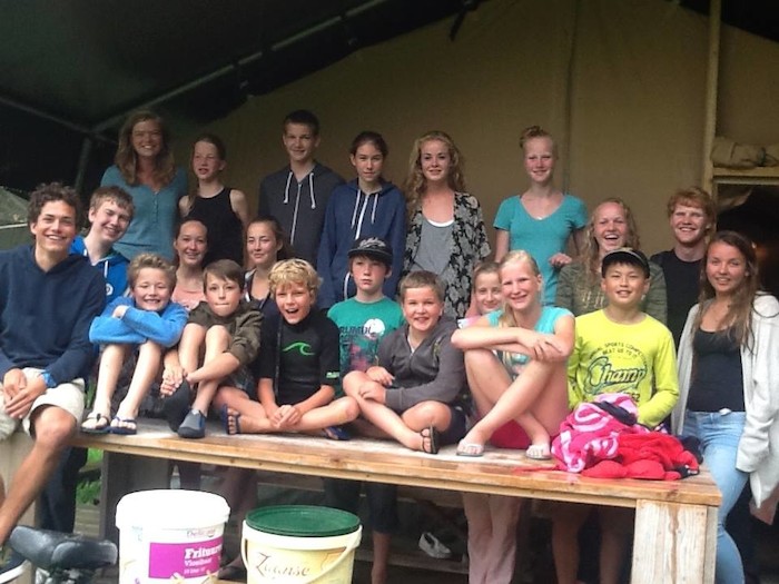Deelnemers poseren lachend met begeleiders op zomerkamp Amsterdam.